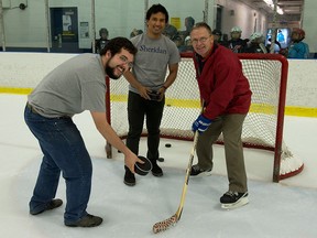 Sheridan College student designers Ryan Veiera, left, and Kristoffer Pascual, centre, pose with consultant Steve Pollard, and their specially-designed hockey puck for the blind on July 30, 2015 in Oakville, Ont. THE CANADIAN PRESS/Jon Blacker