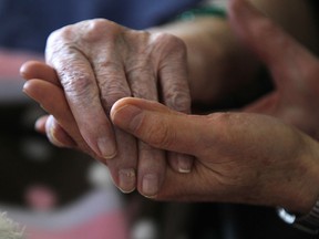 A care giver holds the hand of a long-term care resident in this 2011 file photo. (JASON KRYK/The Windsor Star)
