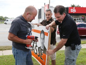 Greg Price and  Albert Mady assist Brian Masse with installing the first campaign sign on Tecumseh Road west in Windsor, Ontario on Aug. 4, 2015.  (JASON KRYK/The Windsor Star)
