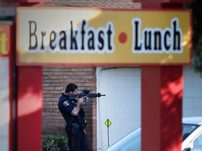 A Windsor police officer trains his gun while police attempt to talk a man out of a hotel room on Howard Avenue near E.C. Row in Windsor.    More than seven police cruisers  and over a dozen officers were on scene.  At least one person was taken into custody at the scene. (JASON KRYK/The Windsor Star)