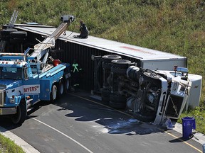 Tow truck crews work to right a rolled over truck at on the on ramp at Howard Avenue and the 401 in Windsor on Tuesday, Aug. 4, 2015. The driver suffered minor injuries when the truck, which was carrying a printing press, rolled.                          (TYLER BROWNBRIDGE/The Windsor Star)
