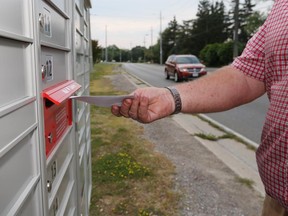 WINDSOR, ONTARIO - AUGUST 17, 2015 - An area resident places mail in a new  Canada Post mailbox in the 11000 block of Riverside Drive east in Windsor, Ont. on Aug. 17, 2015.  (JASON KRYK/The Windsor Star)