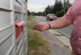 WINDSOR, ONTARIO - AUGUST 17, 2015 - An area resident places mail in a new  Canada Post mailbox in the 11000 block of Riverside Drive east in Windsor, Ont. on Aug. 17, 2015.  (JASON KRYK/The Windsor Star)