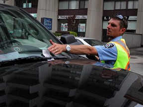 A bylaw enforcement officer issues a ticket on Park Street West on Tuesday, Aug. 18, 2015. (NICK BRANCACCIO/The Windsor Star)