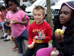 Alex Badgley, 9, centre, and Kiana Bascom, 10, right, enjoy fresh fruit and bagels as Windsor-built Dodge Grand Caravan and Chrysler Town and County minivans arrived filled with dozens of backpacks and school supplies during a wrap-up event for United Way Summer Lunch program Thursday August 27, 2015. The Summer Lunch program provides healthy meal for children who rely on school nutrition programs.  The Back To School Supply Drive and Summer Lunch programs had several sponsors including FCA Windsor Assembly Plant, Staples on Ouellette Ave., CAW Local 444, Farrow, Caesars Windsor, Harvey Strosberg,  Sutts, Strosberg LLP, Bart Seguin at Shibley Righton LLP, Unemployed Help Centre, Hotel-Dieu Grace Healthcare, Windsor Essex Community Housing Corp. and both school boards. (NICK BRANCACCIO/The Windsor Star)