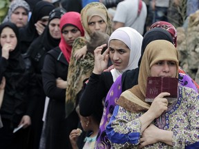 In this Sept. 7, 2015 file photo, Syrian women wait in line to receive aid from an Islamic relief agency at a refugee camp in the town of Ketermaya, north of the port city of Sidon, Lebanon. The United Arab Emirates on Wednesday, Sept. 9, 2015, defended its response to the Syrian refugee crisis in the face of criticism that the country and other oil-rich Gulf states should be doing more to address the issue. (AP Photo/Bilal Hussein, file)