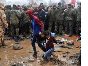 Migrants and refugees wait in the mud and under the rain to cross the Greek-Macedonian border near the village of Idomeni, in northern Greece on September 10, 2015. More than 10 thousands refugees and migrants arrived in Piraeus from the overcrowded Greek islands, especially the island of Lesbos , in the last 24 hours.