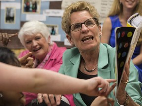 Ontario Premier and Liberal Leader Kathleen Wynne sits with Liz Sandals as she reads to a full day kindergarten class at Westwood Public School in Guelph, Ontario on Wednesday May 14 , 2014. THE CANADIAN PRESS/Chris Young