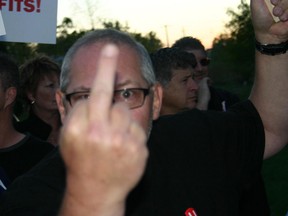 A protester flips the camera the bird at a protest outside Jeff Watson's office. (Photo posted by Jeff Watson to Facebook)