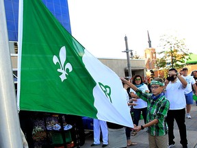 City councillor Fred Francis, left, assists students Owen Drouillard, right, and Dalia El-Mais, behind, at flag raising ceremony during Franco-Ontarian Day at City Hall September 25, 2015.