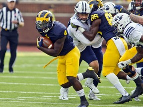 Michigan running back De'Veon Smith (4) breaks away from BYU defenders to rush across the field for a touchdown in the second quarter of an NCAA college football game in Ann Arbor, Mich., Saturday, Sept. 26, 2015. (AP Photo/Tony Ding)