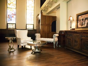 Set near a refurbished carved wooden cabinet original to the former Our Lady of the Rosary Catholic Church are Decor-Rest’s white leather-fronted and cream and taupe fabric-backed wingchair and Pulaski’s distressed grey bench featuring intricate wood carving and a cream button-tufted fabric seat. The smaller accent mirrored table is also by Pulaski; the mirrored coffee table is by Decor-Rest. Everything, including the painting and lamps, are from Coulter’s Furniture.
- Photo courtesy LiquidWild Media