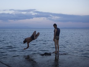 Syrian refugees jump into the sea near the port of Mitylene on the northeast Greek island of Lesbos, Tuesday, Sept. 8, 2015, while waiting to get on board a ferry traveling to Athens. The island of some 100,000 residents has been transformed by the sudden new population of some 20,000 refugees and migrants, mostly from Syria, Iraq and Afghanistan. (AP Photo/Santi Palacios)
