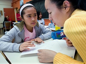Grade 4  student Anissa Esguerra (left) helps Jing Shi from China, with a French lesson in Montreal. (Postmedia News files)