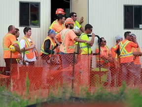 Distraught parkway workers look on as rescue crews work the scene after a worker was killed in an industrial accident at the Herb Gray Parkway in LaSalle, Ont. on June 17,2014. The Ontario Provincial Police are investigating the industrial accident. (JASON KRYK/The Windsor Star)