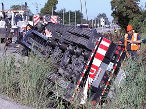 Tow truck operators work on righting a semi-truck that rolled over at the intersection of Walker Rd. and highway 3 at approximately 7:30 a.m. on Monday, Sept. 14, 2015, in Tecumseh, ON. No injuries were reported. The westbound lanes were closed for several hours.  (DAN JANISSE/The Windsor Star)