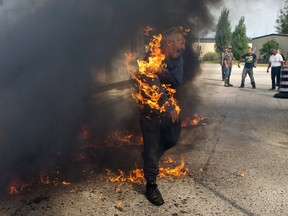 Pierre George is engulfed in flames during a dispute between members of the Kettle and Stony Point First Nations at the entrance to the former army camp being returned by the federal government in Ipperwash, Ont. on Sunday September 20, 2015. Some residents of the camp set a small fire to stop others from entering at the end of a peaceful march to signify the return of the land.  George's brother Dudley was shot and killed by an OPP sniper during an occupation at Camp Ipperwash in 1995.  Craig Glover/The London Free Press/Postmedia Network