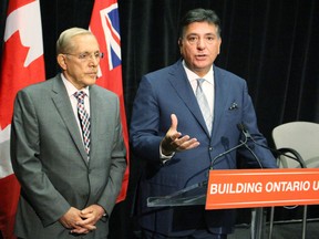 Ontario Energy Minister Bob Chiarelli (left) and Finance Minister Charles Sousa announce on Friday, Sept. 18, 2015, next step in the partial sale of Hydro One - a preliminary prospectus. The pair says the proposed $4 million compensation package for the new CEO is reasonable given that the bulk of it will depend on meeting targets. Antonella Artuso/Toronto Sun/Postmedia Network