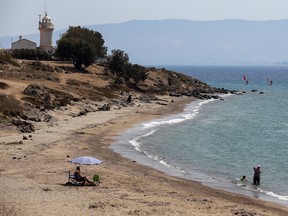 People rest on the same beach where the body of Syrian boy Aylan Kurdi, 3, was found after a boat capsized near the Turkish resort of Bodrum, Turkey, Tuesday, Sept. 8 , 2015. The tides also washed up the bodies of the boy's 5-year-old brother Ghalib and their mother Rehan on Turkey's Bodrum peninsula. Their father, Abdullah, survived the tragedy. (AP Photo/Emrah Gurel)