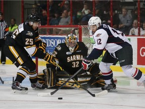 Windsor Spitfires Anthony Stefano, right, handles the puck in front of Sarnia Sting goaltender Justin Fazio and Jordan Kyrou during OHL preseason action at the WFCU Centre in Windsor, Ontario on September 17, 2015.