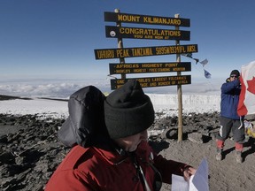 Richard Vennettilli, left, and Dante Morassutti at Uhuru Peak on Mount Kilimanjaro. Richard is reading a message from MP Jeff Watson. Morassutti is holding up Canadian flag given to the KiliKlimb 2015 team by Watson.