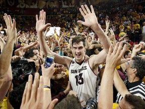 Arizona State's Jordan Bachynski (13) celebrates with fans after an NCAA college basketball game win against Arizona, Friday, Feb. 14, 2014, in Tempe, Ariz.  Arizona State defeated Arizona 69-66 in double overtime. (AP Photo/Ross D. Franklin)