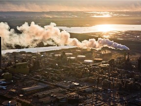 FORT MCMURRAY, ALTA.:      JUNE, 18, 2013:  The setting sun reflects off a tailings pond behind Syncrude's oilsands upgrading facility north of Fort McMurray, Alta. on June 18, 2013. The plant converts bitumen which is extracted from oilsands into synthetic crude oil which is then piped to southern refineries. Alberta's oilsands are the third largest proven oil reserve in the world. (Ryan Jackson / Edmonton Journal) ORG XMIT: POS1308151929380567 ORG XMIT: POS1312191837084885