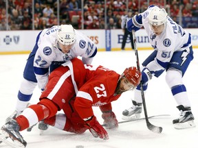 Detroit Red Wings defenseman Kyle Quincey (27) protects the puck from Tampa Bay Lightning right wing Erik Condra (22) and Valtteri Filppula (51) during the first period of an NHL hockey game in Detroit, Tuesday, Oct. 13, 2015. (AP Photo/Paul Sancya)