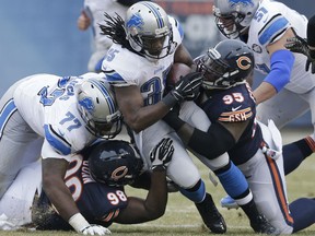 Detroit Lions running back Joique Bell (35) is tackled by Chicago Bears defensive tackles Brandon Dunn (98) and Ego Ferguson (95)in the first half of an NFL football game Sunday, Dec. 21, 2014, in Chicago. (AP Photo/Nam Y. Huh)
