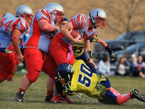 Brennan Cardinals quarterback Liam LeClair, centre, is stopped behind the line of scrimmage by St. Joseph's Lasers Zack Macneill, right, in senior boys football at St. Joseph's field Friday October 23, 2015.  Cardinals linemen Ethan Colombe, left, and Ian Campbell assist on the play. (NICK BRANCACCIO/Windsor Star)