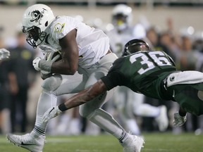 Windsor's Arjen Colquhoun, right, tackles Oregon's Royce Freeman during the first quarter of an NCAA college football game in East Lansing, Mich. (AP Photo/Al Goldis)