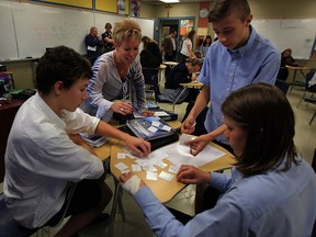 St. Joseph's mathematics teacher Angie Mooney, centre, assists students Brayden Hoare, left, Nicholas Janiak and Devon Thachuk-Gay Oct. 28, 2015.