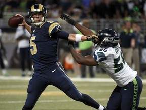 St. Louis Rams quarterback Nick Foles, left, throws under pressure from Seattle Seahawks defensive end Cliff Avril during the overtime of an NFL football game Sunday, Sept. 13, 2015, in St. Louis. (AP Photo/L.G. Patterson)