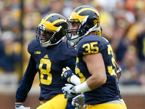 Channing Stribling #8 of the Michigan Wolverines celebrates a first quarter interception with Joe Bolden #35 while playing the UNLV Rebels on September 19, 2015 at Michigan Stadium in Ann Arbor, Michigan.  (Photo by Gregory Shamus/Getty Images)