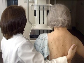 A mammographer prepares a woman for a digital mammogram.