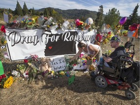 Candida Miller, left, and Brandon Snyder leave flowers at a site of a growing memorial to victims of the mass shooting at Umpqua Community College in Roseburg, Ore., Tuesday, Oct. 6, 2015.