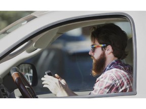 FILE - In this Feb. 26, 2013 file photo, a man uses his cell phone as he drives through traffic in Dallas. In a new survey, 98 percent of motorists who own cellphones and text regularly were aware of the dangers, yet three-quarters of them admit to texting while driving, despite laws against it in some states. Two-thirds said they have read text messages while stopped at a red light or stop sign, while more than a quarter said they have sent texts while driving.