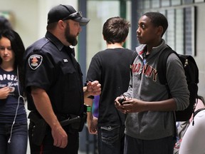 Windsor Police Const. Craig Judson chats with a student in the halls of Herman Secondary School on Wednesday, Oct 7, 2015. He is part of a special program that designates an officer to patrolling high schools.