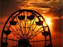 Patrons ride the Windsor Summerfest carnival ferris wheel by the river as the sun sets on a warm summer's evening.