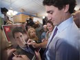 Liberal Leader Justin Trudeau signs a poster for a supporter during a campaign stop at a Greek restaurant, Thursday, Oct. 15, 2015 in Laval, Que.