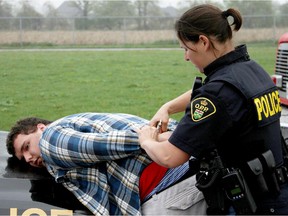 Student actor Riley Charron is arrested as part of a Mock Drinking and Driving Accident Simulator, Wednesday. Emergency crews and student actors from St. Anne Catholic High School performed the presentation behind the school. The message is aimed at students with prom season right around the corner. (PHOTO BY RICK DAWES/The Windsor Star)
