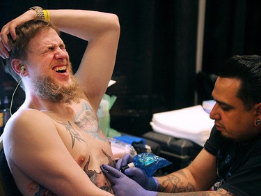 Ryan Maljak grimaces in pain as he gets a stomach tattoo from artist Frodo of Texas during the Motor City Tattoo Expo in Detroit, Mich. on Saturday, March 7, 2015.