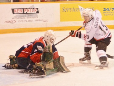 Owen Sound Attack's Bryson Cianfrone, right, tries to shovel a shot past Windsor Spitfires goalie Michael Giugovaz during the first period of Sunday's game.