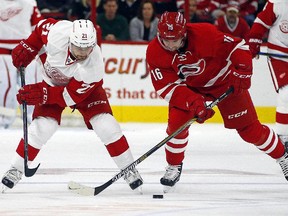 Detroit Red Wings' Tomas Tatar (21) battles with Carolina Hurricanes' Elias Lindholm (16) of Sweden, during the first period of an NHL hockey game, Saturday, Oct. 10, 2015, in Raleigh, N.C.