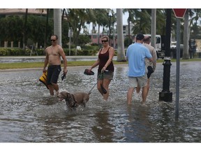 People walk through a flooded street that was caused by the combination of the lunar orbit which caused seasonal high tides and what many believe is the rising sea levels due to climate change on Sept. 30, 2015, in Fort Lauderdale, Florida.  South Florida is projected to continue to feel the effects of climate change and many of the cities have begun programs such as installing pumps or building up sea walls to try and combat the rising oceans. (Photo by Joe Raedle/Getty Images)