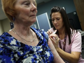 Sue Wilkinson receives her flu shot from nurse Monique Hayes during a press conference at the The Windsor-Essex County Health Unit in Windsor on Thursday, October 15, 2015.