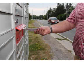 An area resident places mail in a new  Canada Post mailbox in the 11000 block of Riverside Drive east in Windsor, Ontario on Aug. 17, 2015. (JASON KRYK/The Windsor Star)