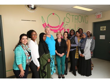 Staff and clients from the Women's Enterprise Skills Training of Windsor Inc. (West) stand with the    Strong Girls Strong World mural that consists of positive and inspirational messages from the public. The mural will highlight the International Day of the Girl, held on Oct 11,2015.