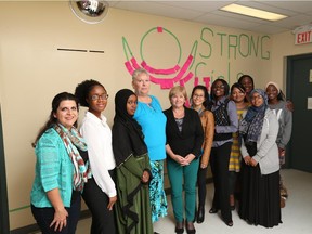 Staff and clients from the Women's Enterprise Skills Training of Windsor Inc. stand with the Strong Girls Strong World mural that consists of positive and inspirational messages from the public. The mural will highlight the International Day of the Girl, held on Sunday, Oct. 11, 2015.