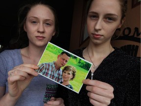 Payton Desbiens, 18, left, and her sister Madison Desbiens, 16, hold a photograph of their parents, Kerri and Robert Desbiens, who both died within weeks of each other. To make matters worse, thieves broke into their home recently and stole many of their possessions, including family heirlooms and photographs.
